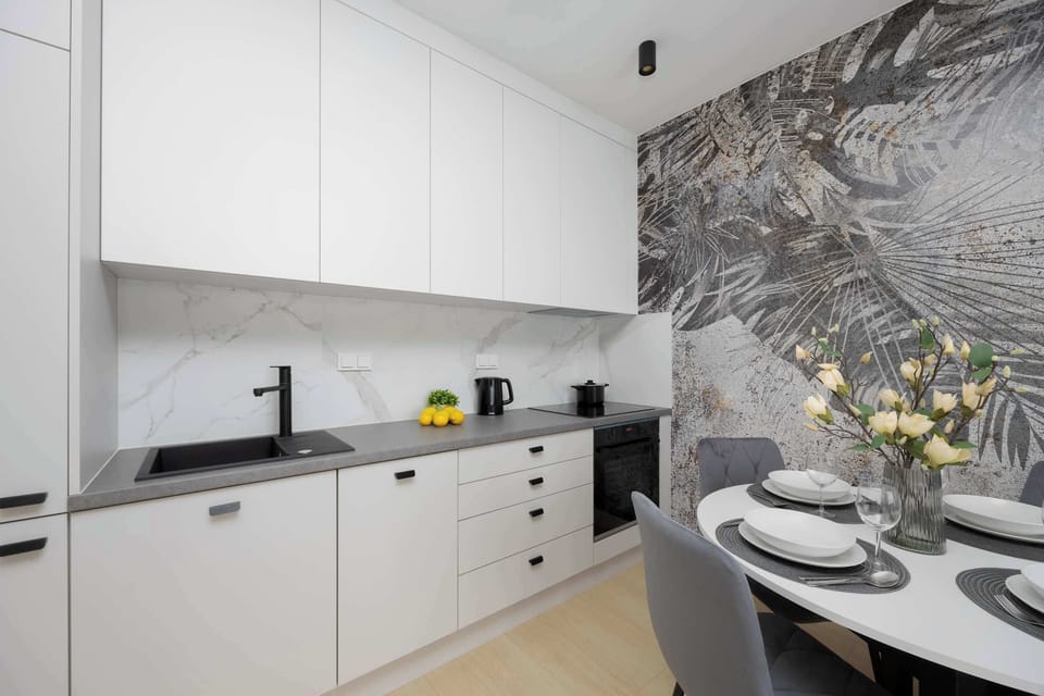 A compact kitchen area featuring white cabinets, subtle lighting, and a minimalist look.