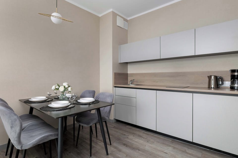A modern kitchen with white cabinetry and an elegant dining area. The setup is both stylish and practical for everyday use.