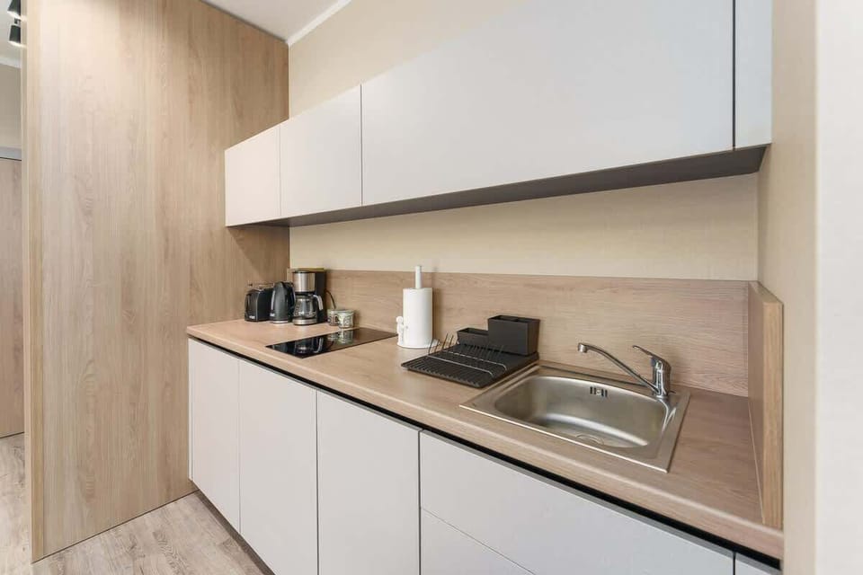 A minimalist kitchen design with white cabinetry, a wooden backsplash, and a clean layout.
