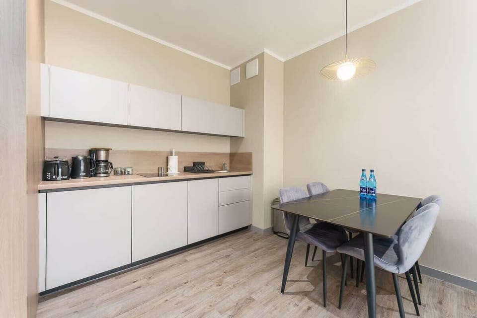 A sleek and compact kitchen with white cabinets, wooden finishes, and a small dining table.
