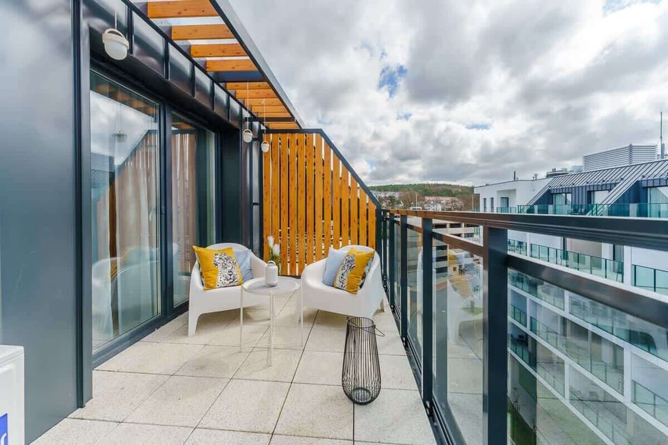 A close-up of a balcony with cozy seating, glass railings, and scenic views of the surrounding area.
