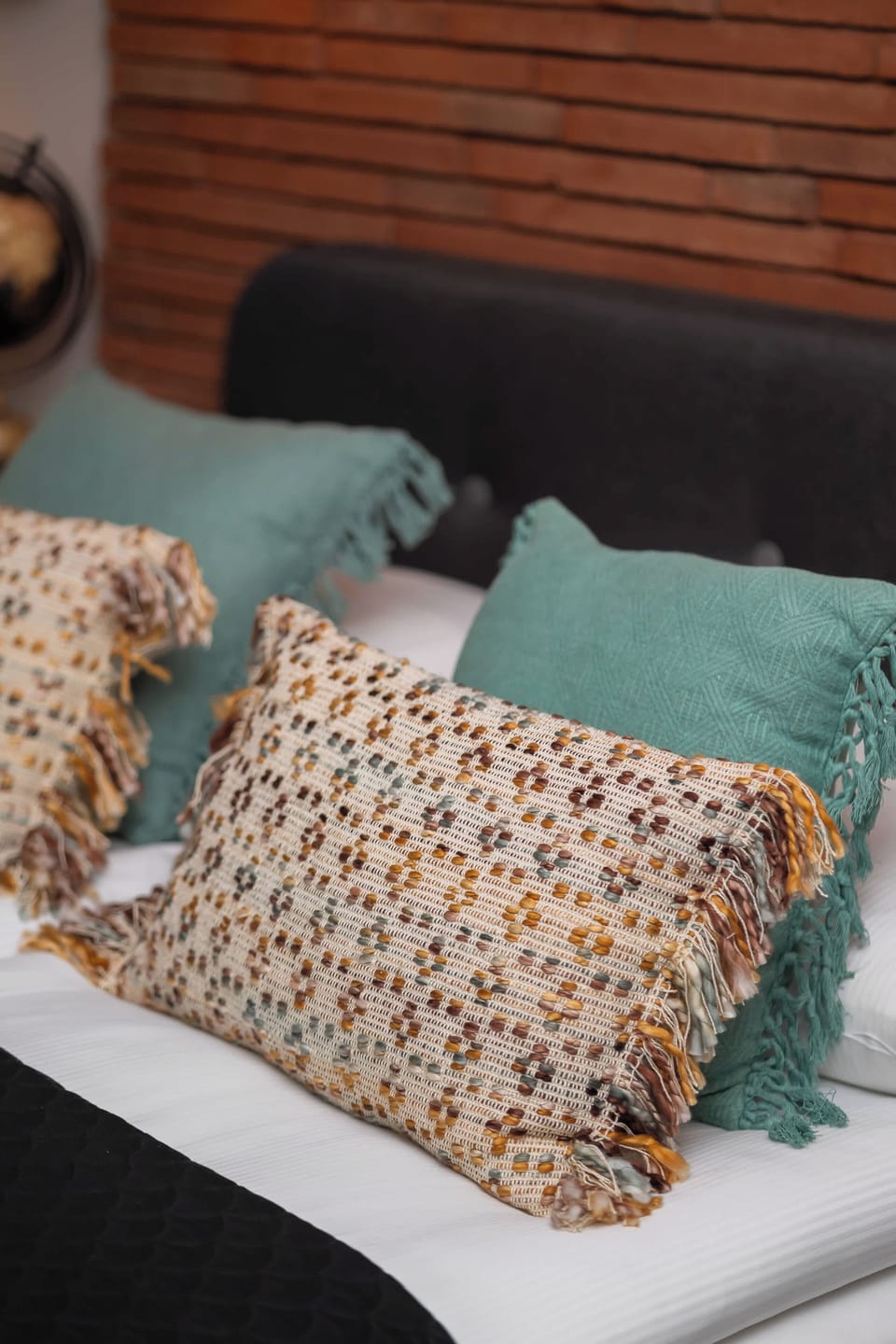 A close-up of a bed with patterned pillows, showing the details of the textured fabric. The bed has a cozy and stylish look.