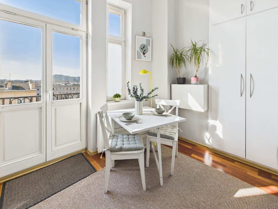 Table with chairs by a large window, filling the room with daylight.