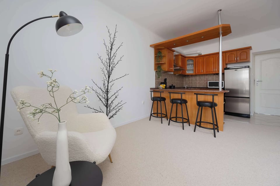 Bright living room with modern furniture, a comfortable sofa, and a coffee table seamlessly connects with the open kitchen, offering a comfortable space for relaxation and gatherings.