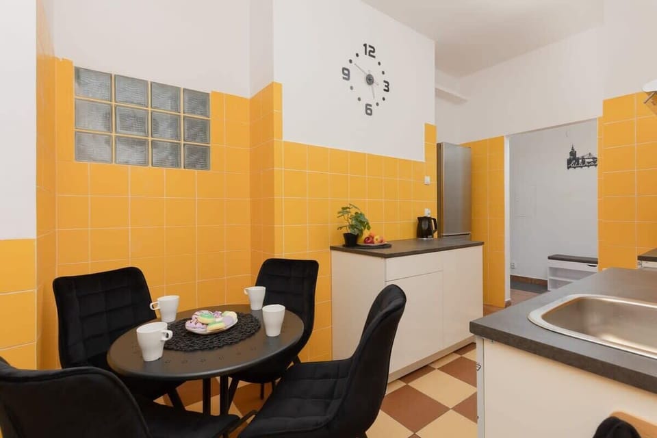 A small but charming kitchen area with a yellow tiled wall and dining table. The layout is efficient and full of character.
