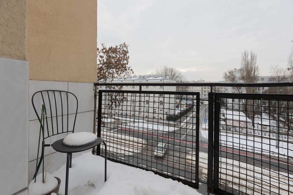 A balcony with a small table and chairs, ideal for morning coffee. Snow on the railing adds a touch of winter charm.