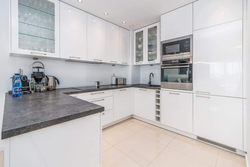 A well-equipped kitchenette with white furniture that matches the design of the bright living room. 