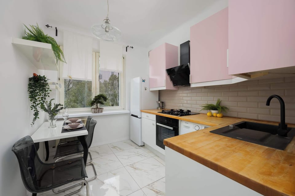 A modern kitchen with pink cabinets and a wooden countertop combines functionality with unique design.