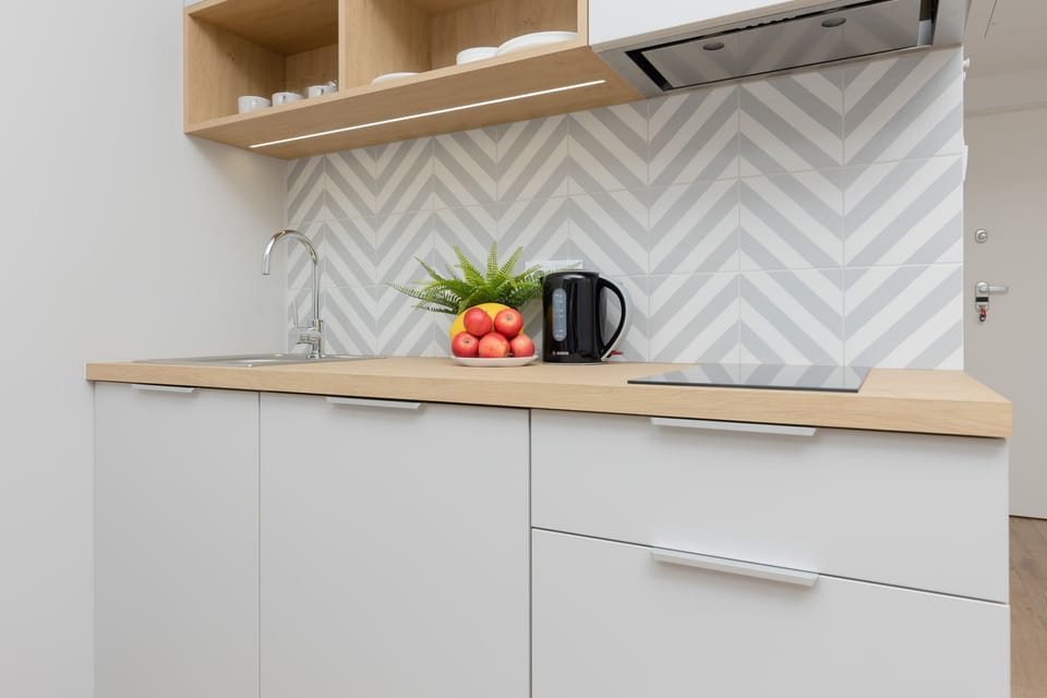 A modern kitchen corner with white cabinets and sleek appliances, paired with geometric backsplash tiles for a contemporary look.