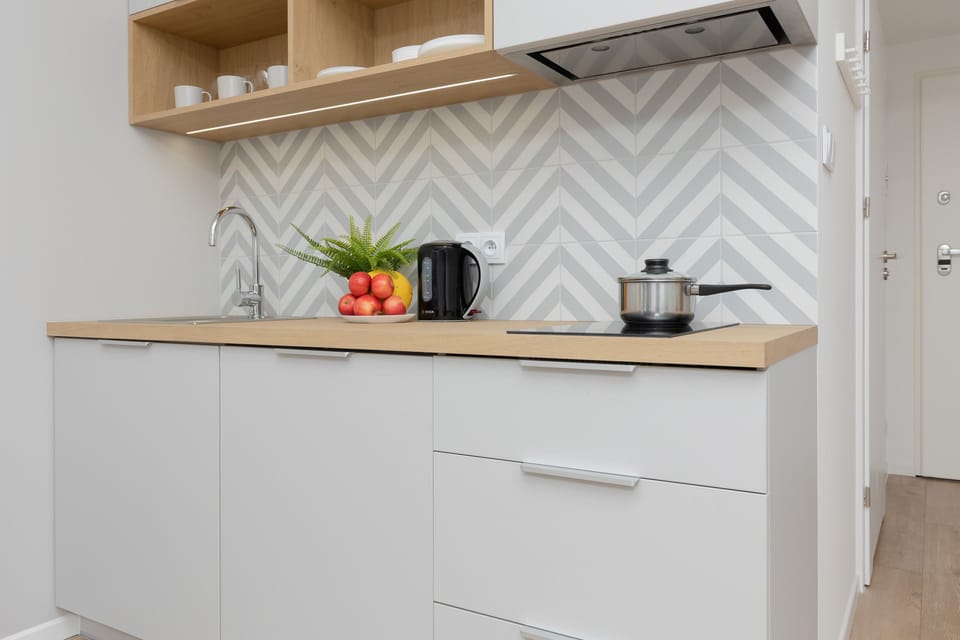 A modern kitchen corner with white cabinets and sleek appliances, paired with geometric backsplash tiles for a contemporary look.