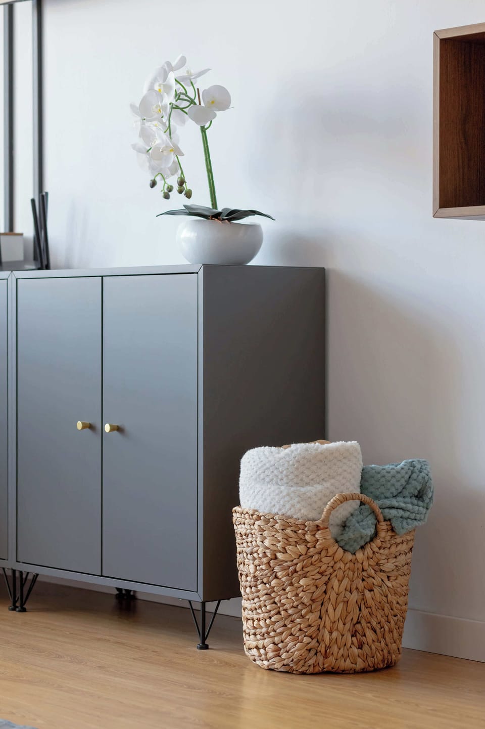 Decorative cabinet area with potted plant, baskets, and soft lighting.