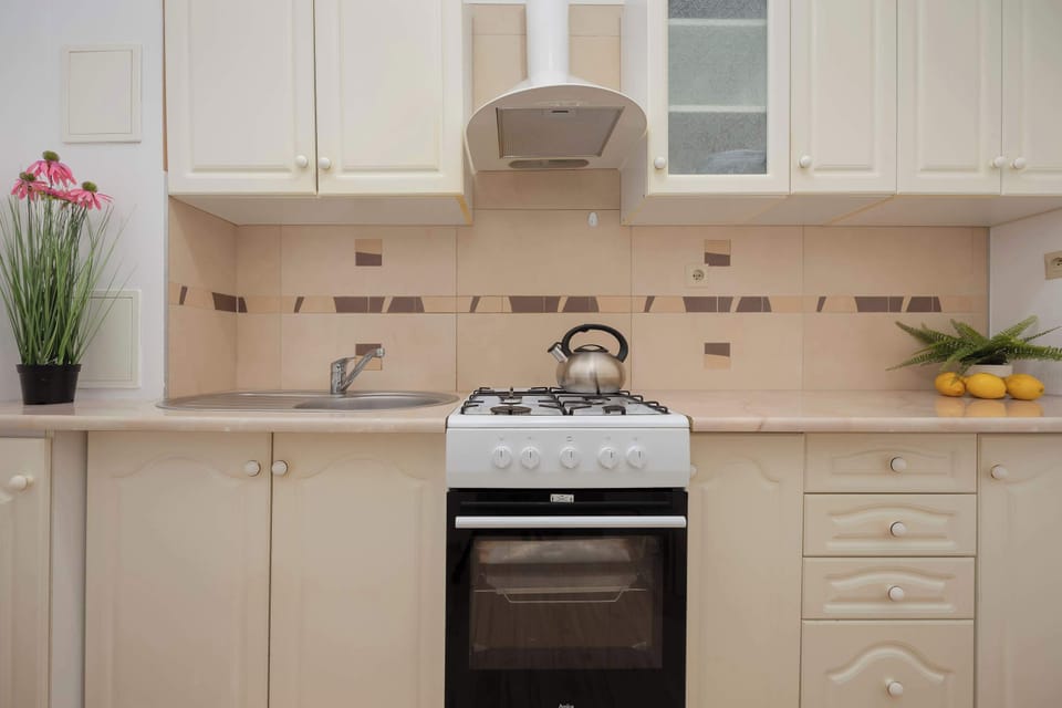 Beige kitchen with gas stove, oven, refrigerator with freezer and gas kettle.