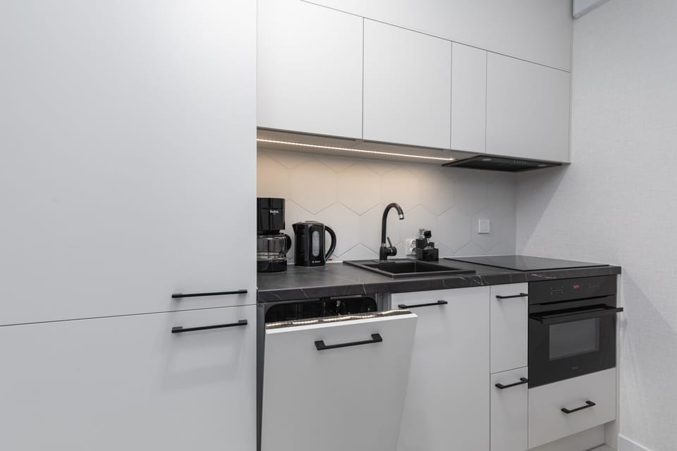 A close-up of the modern kitchen and counter, equipped with a sink, stove, and elegant black fixtures.