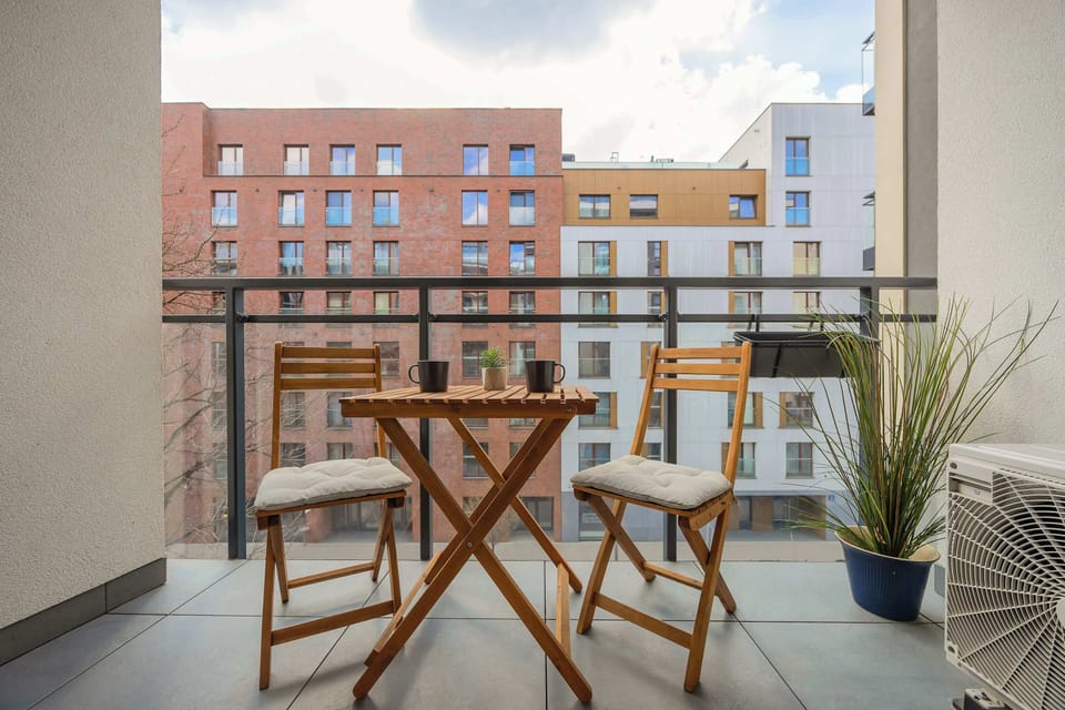 A charming balcony with a small table and chairs. The view overlooks a neighboring building.