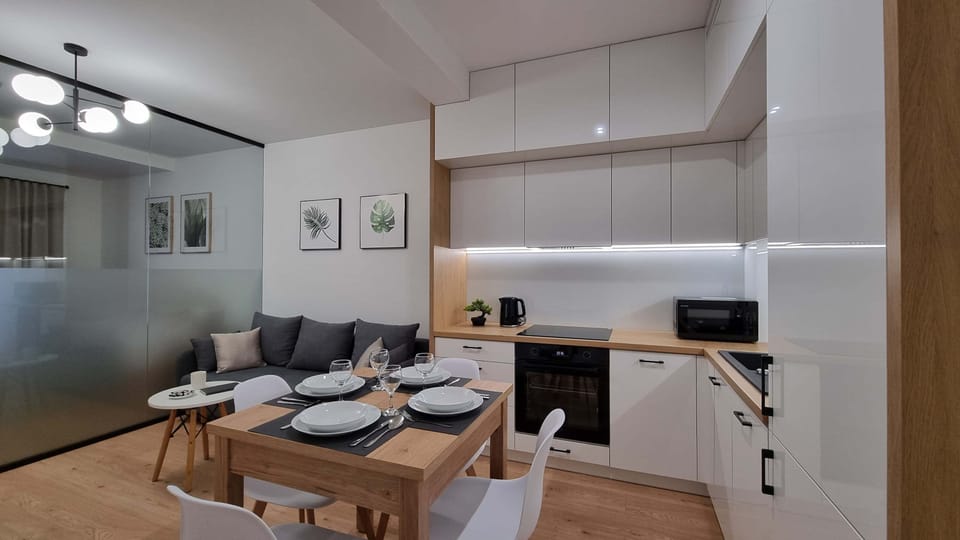 Another angle of the kitchen and dining area, emphasizing the clean and bright design. The kitchen features a contemporary style with white cabinetry and simple decor.