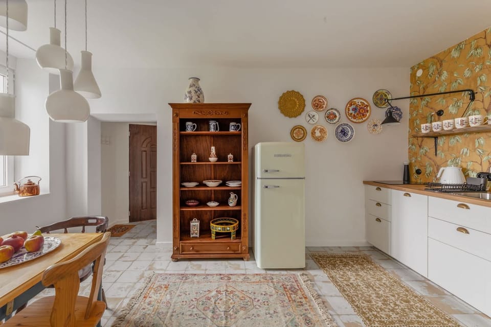 A farmhouse-style kitchen with white cabinets, open shelving, and cozy decor, blending functionality with charm.