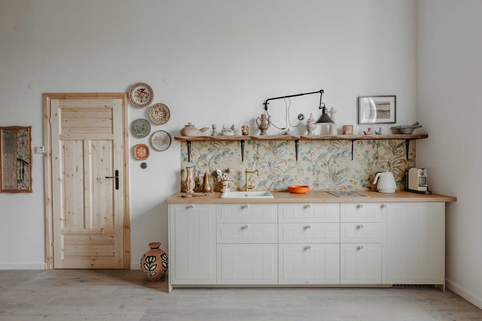 A farmhouse-style kitchen with white cabinets, open shelving, and cozy decor, blending functionality with charm.