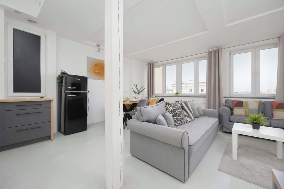 A modern living room with a grey sofa, white coffee table, and large windows letting in lots of natural light.