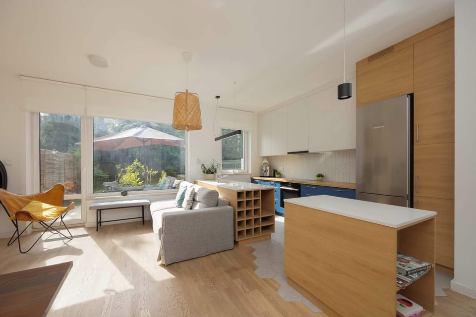 Modern, fully equipped kitchen open to the living room, with elegant fronts and appliances: refrigerator, freezer, oven, induction hob.