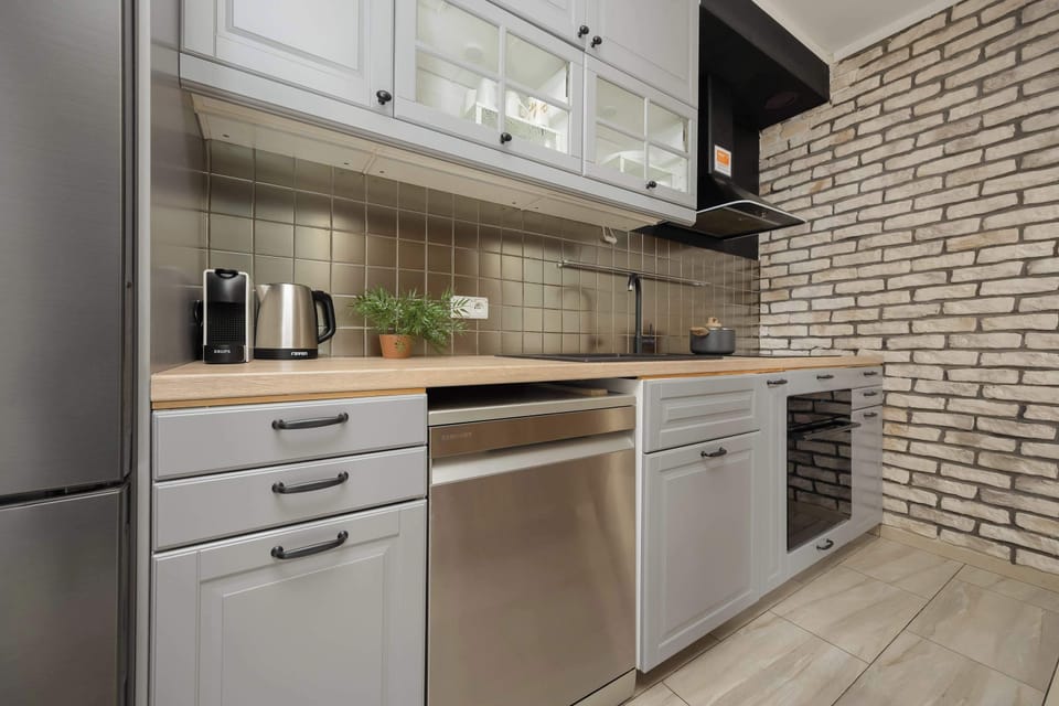 A sleek kitchen with built-in appliances, tiled backsplash, and wood-accented cabinetry.