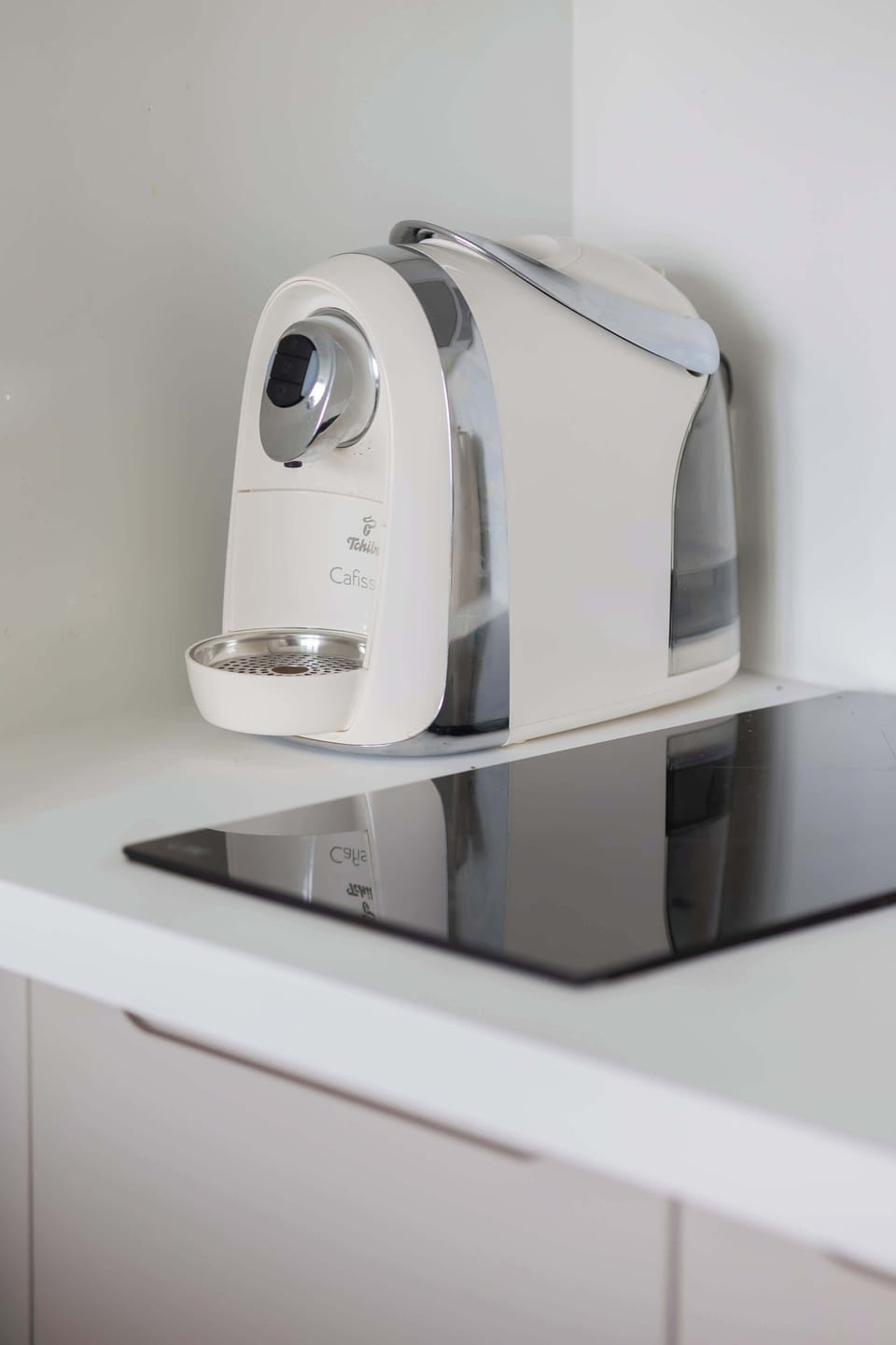 The studio includes a compact coffee station with a pod machine placed on a sleek induction stove.