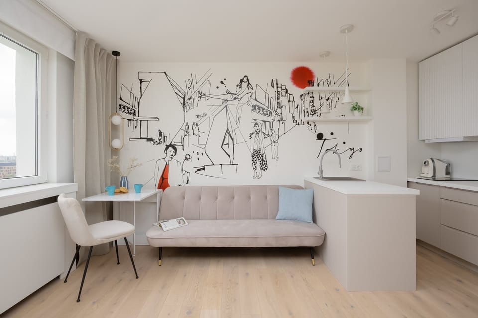 The studio features a cozy bed area with large windows that let in plenty of natural light.