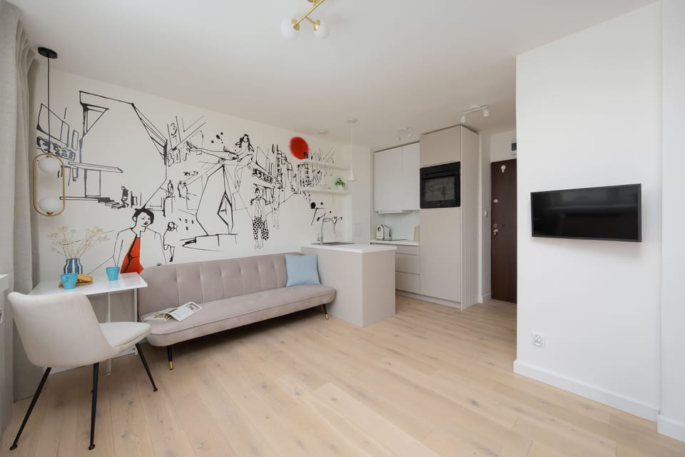A neatly arranged sleeping space with wall-mounted TV and built-in shelves above the bed adds functionality to the studio.