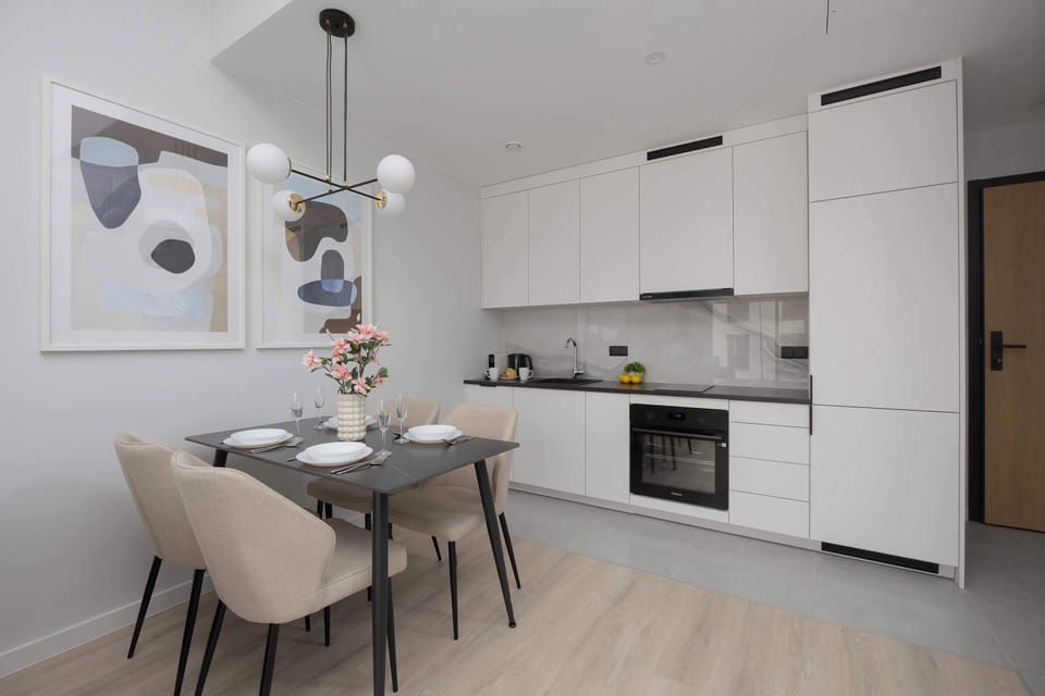 A modern kitchenette open to the living room, equipped with elegant furniture, functional appliances, and a stylish range hood.