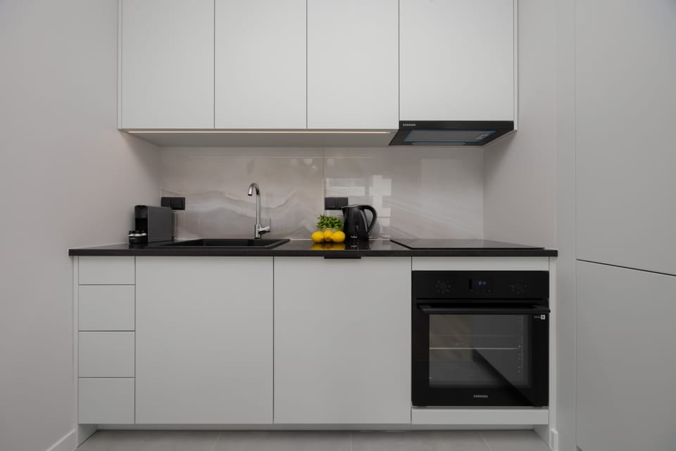 A neatly organized kitchen and dining nook, showcasing modern cabinetry, a ceramic cooktop, and stylish seating.

