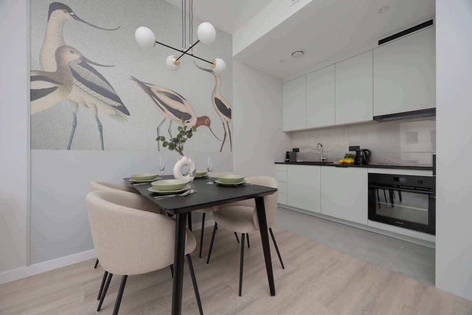 A well-equipped kitchen corner with sleek white cabinets, black countertop, and integrated appliances.
