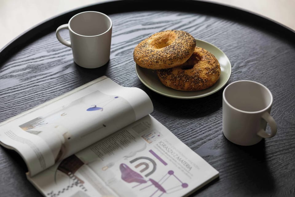 A breakfast setup with fresh pastries and coffee mugs, placed on a round black table.