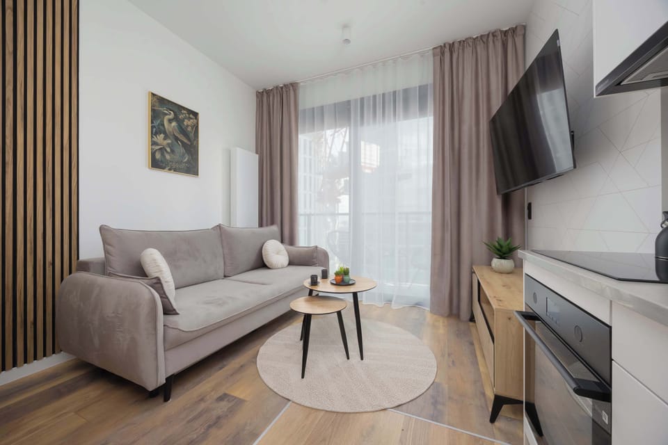 A bright living room with a beige sofa and sheer curtains invites relaxation in a peaceful setting.