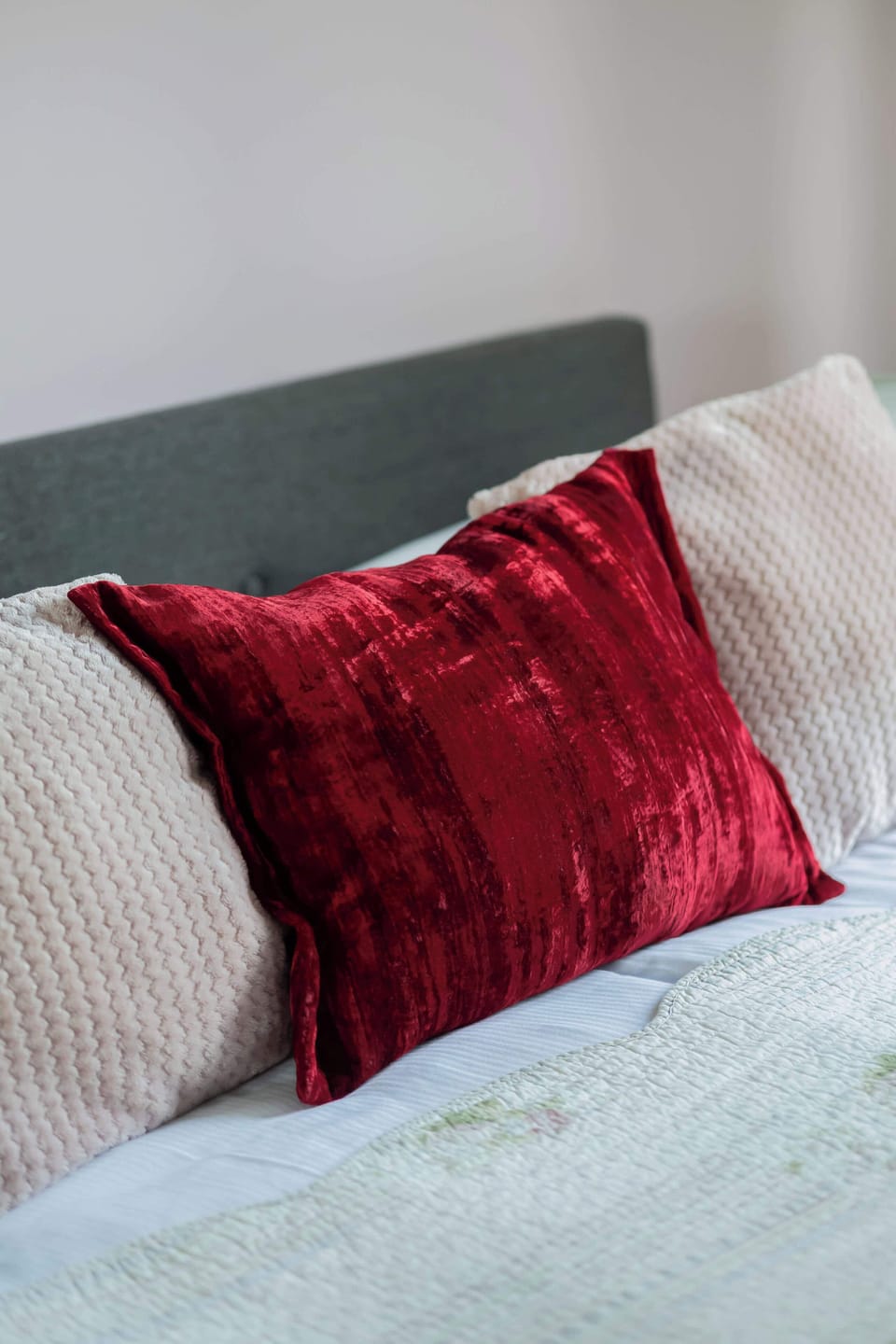 A close-up of a bed with white sheets and a red pillow. Inviting and comfortable for rest.

