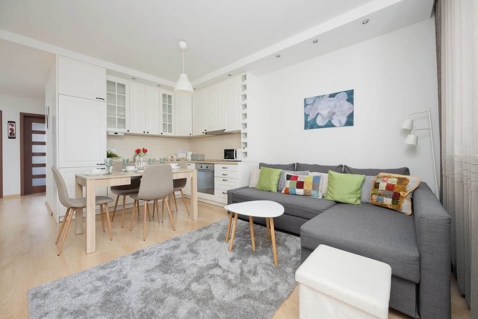 A cozy living room space with a sofa, armchair, and a coffee table on a soft rug. Perfect for relaxing or spending time with loved ones.