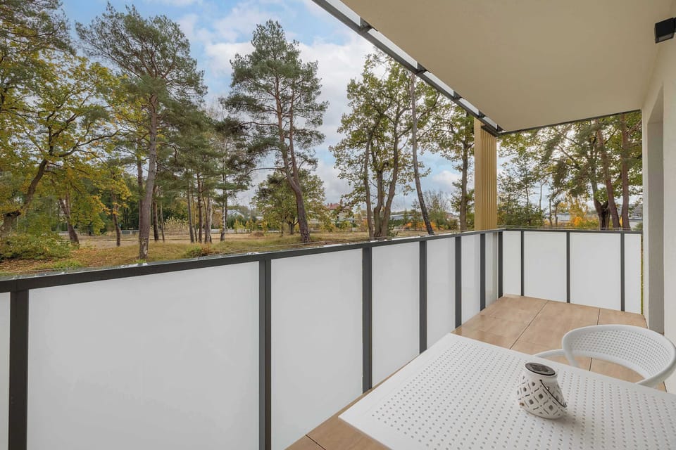 The balcony view, showing a surrounding area of trees and distant buildings, adding to the serene ambiance and offering a pleasant outdoor experience.