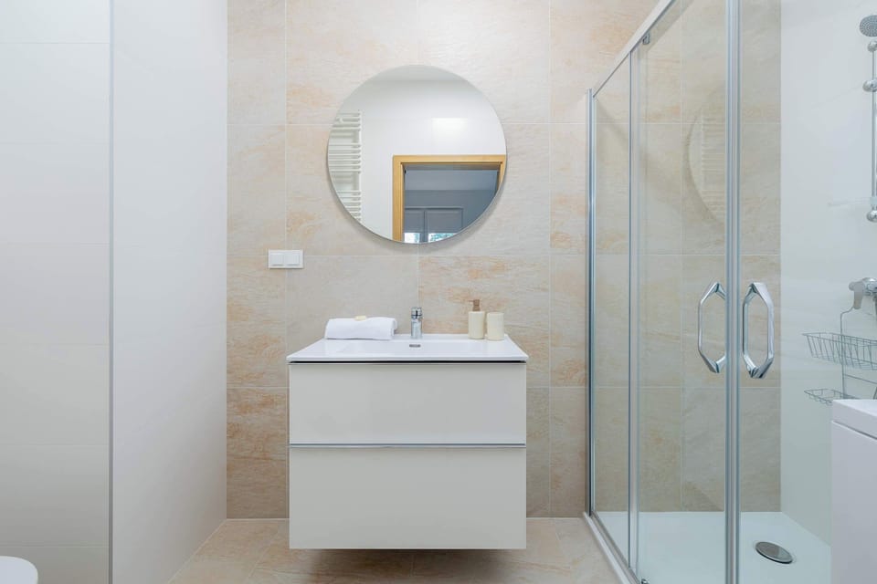The bathroom featuring a modern vanity with a round mirror and well-organized toiletries, providing a clean and functional space.