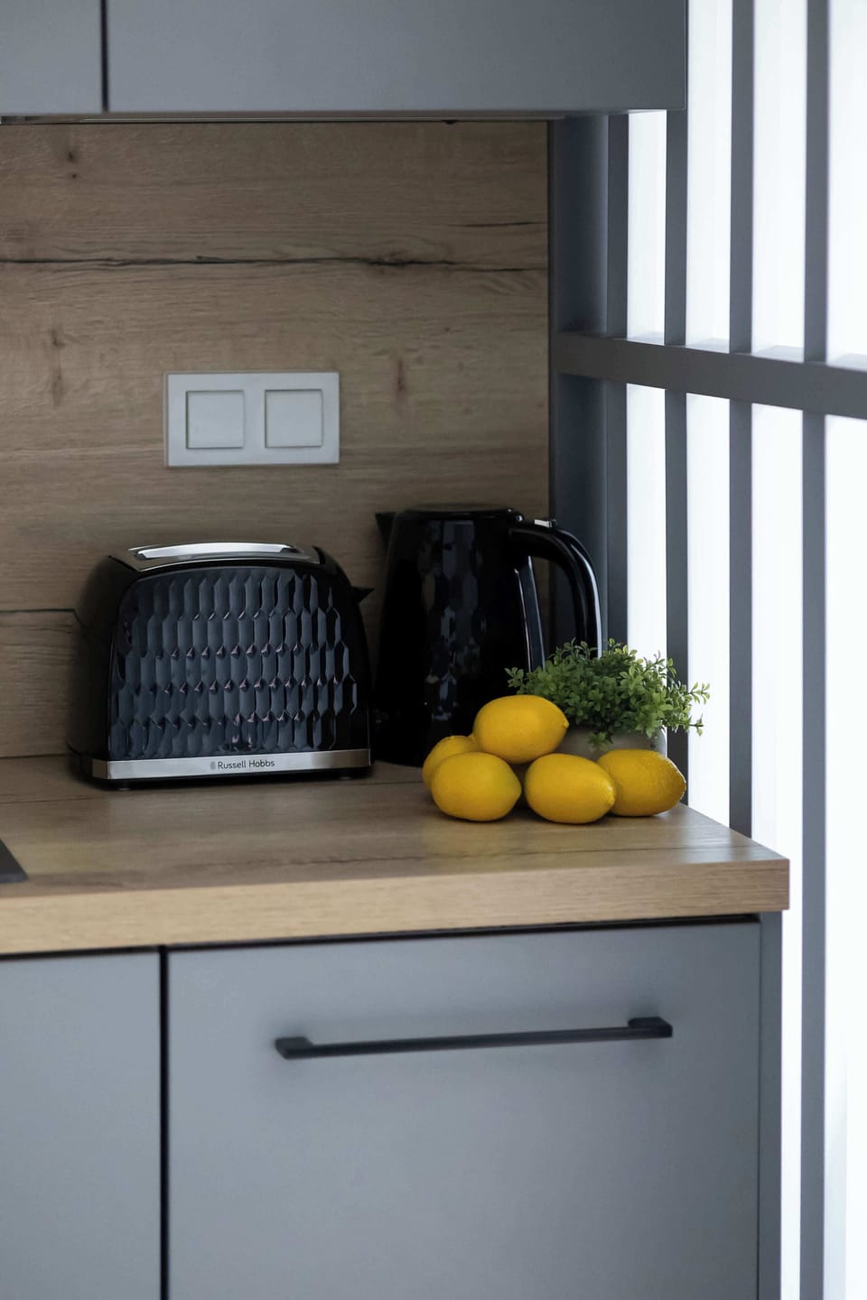 The countertop with lemons and an electric kettle brings a cozy and energizing touch to the kitchen.

