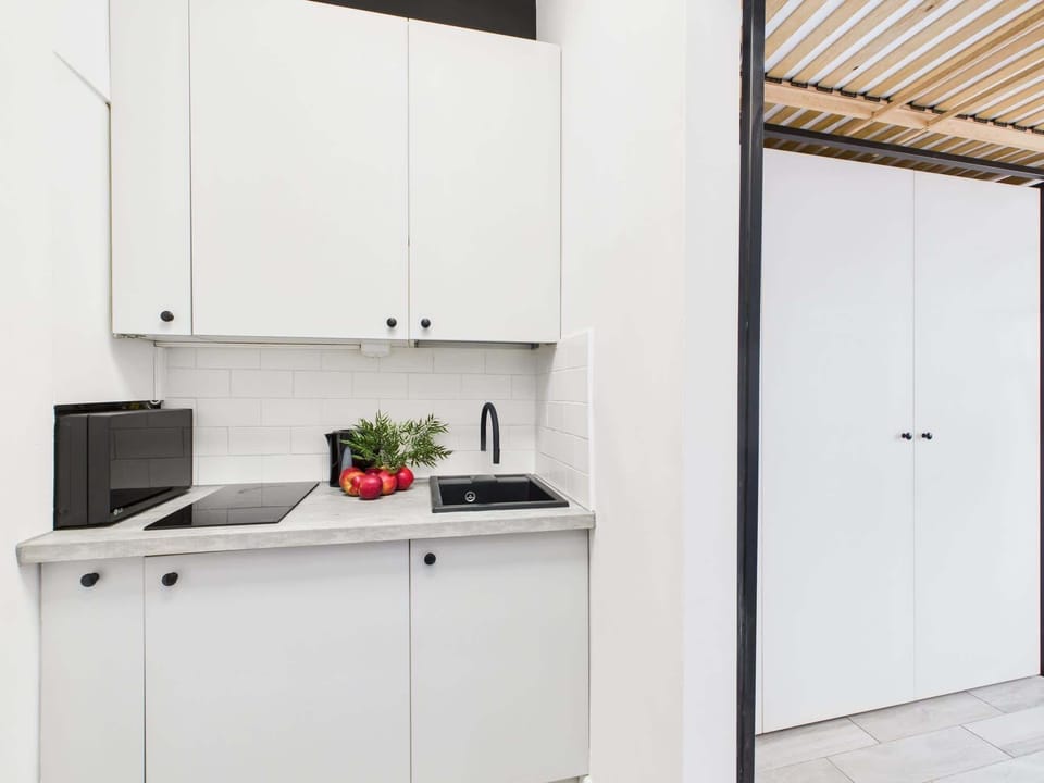 A fully equipped kitchenette with modern white cabinets and a dark countertop that combines aesthetics with functionality.