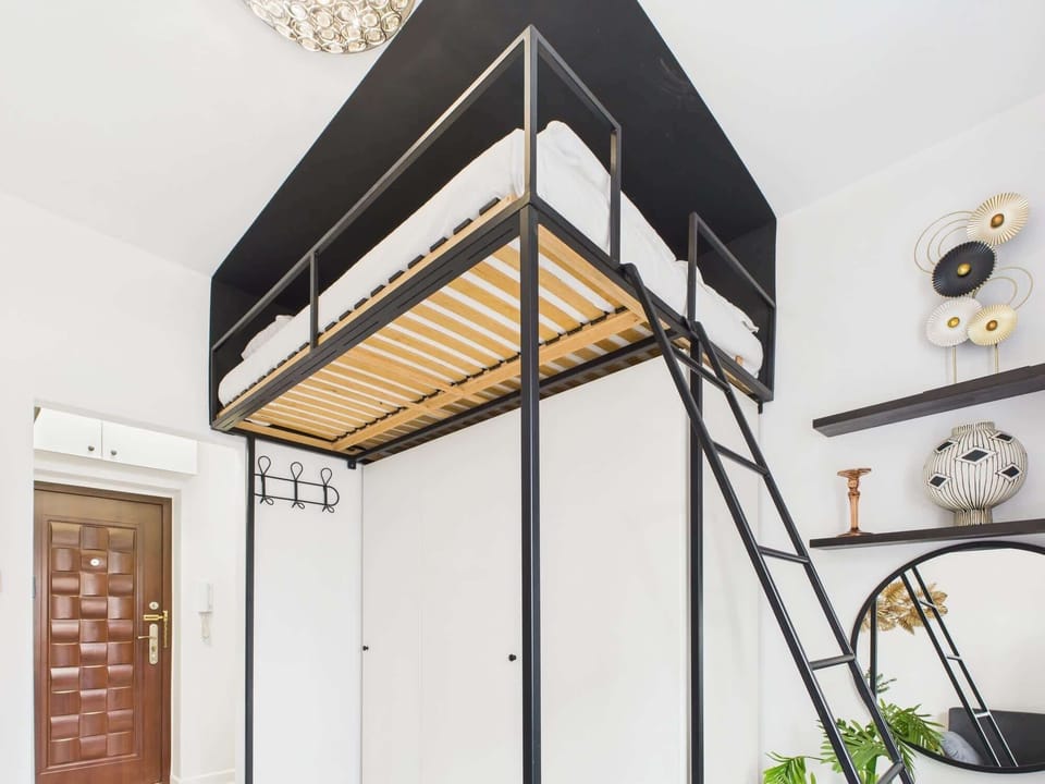 A view of the mezzanine with a bed, highlighting the apartment's height and thoughtful design.