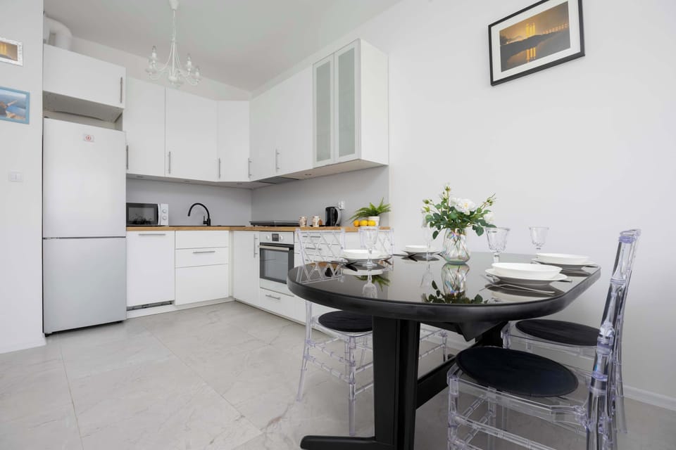 The kitchen features a modern design with a small dining table, offering a compact yet stylish space for cooking and eating.