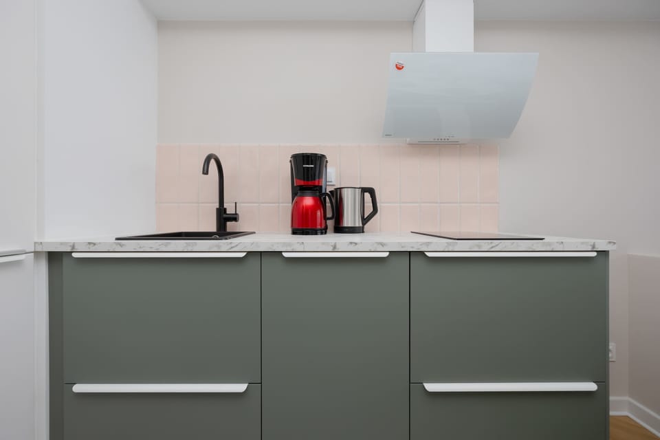 The kitchen with matte green cabinets and modern appliances makes home cooking a real pleasure.

