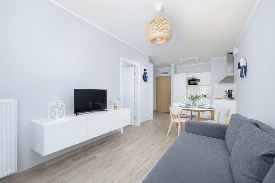 Stylish and elegant living room with television, cabinet, kitchenette, dining area, and double sofa bed.