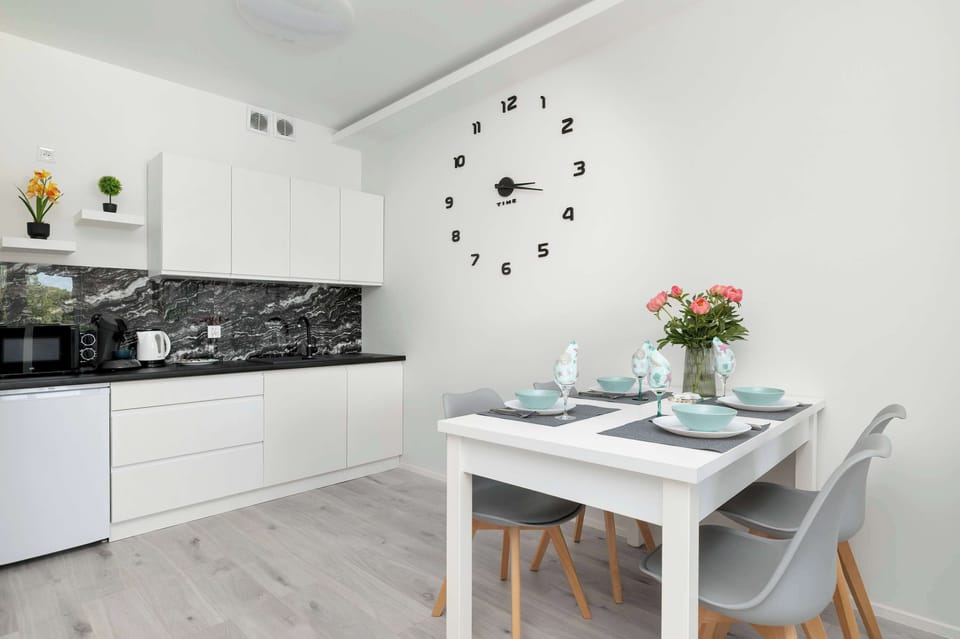 A cozy dining nook adjacent to the kitchen, decorated with fresh flowers and green-themed wall art for a natural accent.

