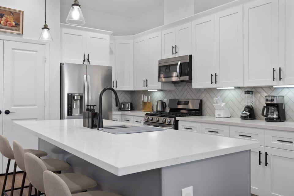 Fully equipped kitchen with quartz island seating, modern appliances, cookware, and all essentials for cooking and entertaining. Kitchen Oasis: Sleek white cabinetry and a spacious island perfect for culinary adventures!