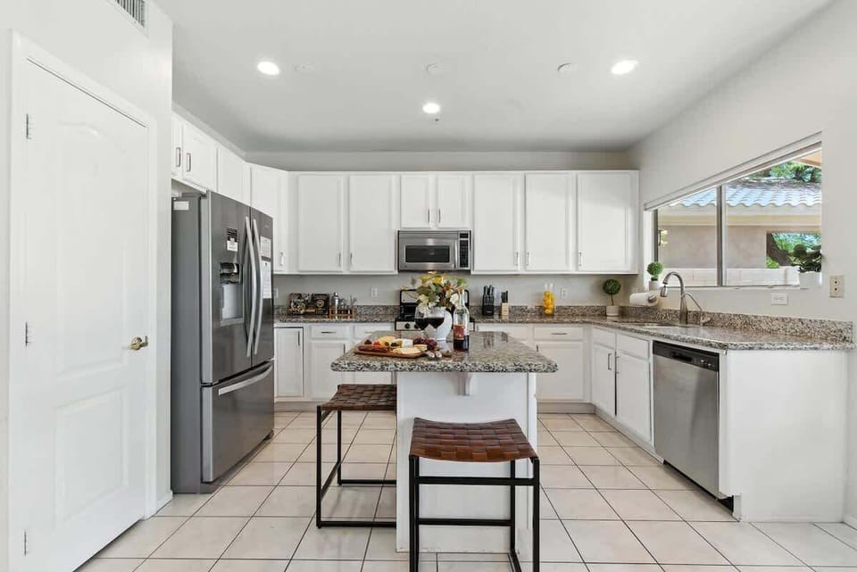 The fully equipped modern kitchen is stocked with all culinary essentials, stainless-steel appliances, and breakfast bar seating. (1st Floor)