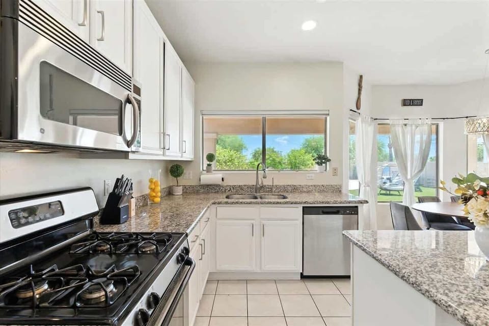 The fully equipped modern kitchen is stocked with all culinary essentials, stainless-steel appliances, and breakfast bar seating. (1st Floor)