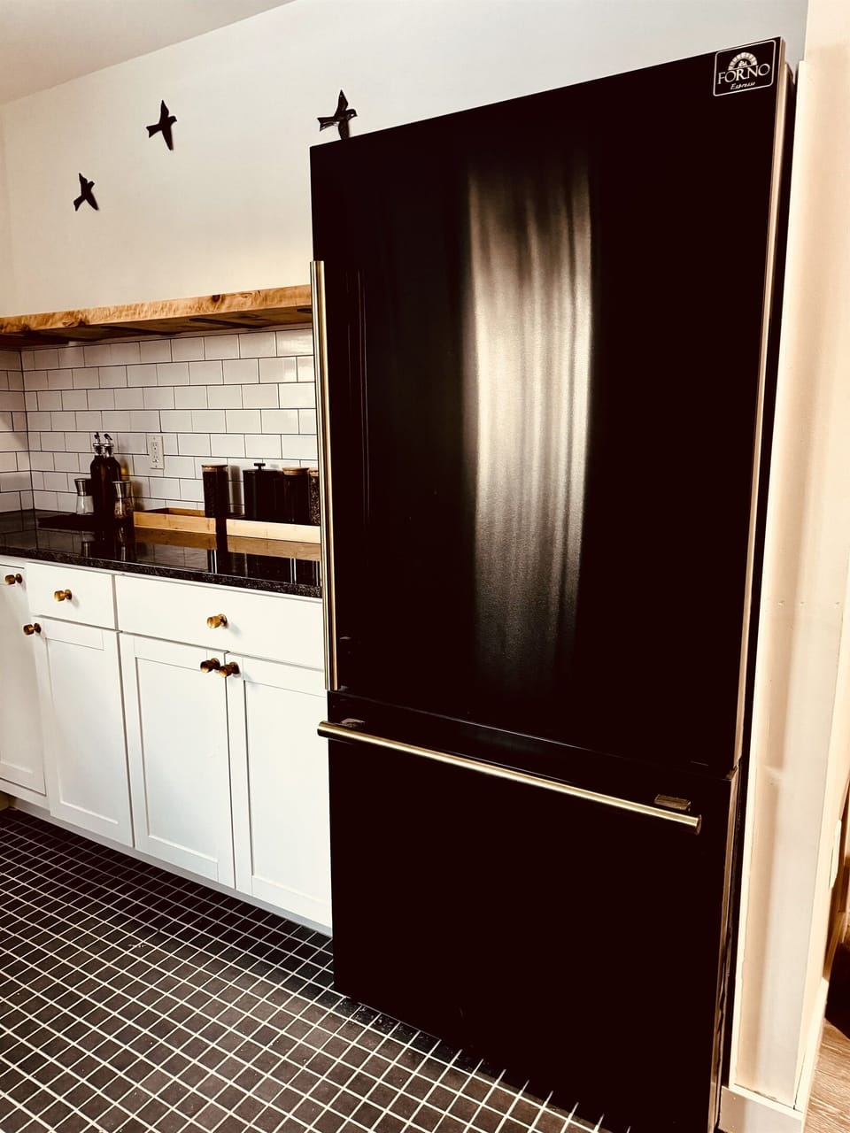 Kitchen is designed in warm white, black and gold colors featuring rustic rough cut shelves crafted by local artists 