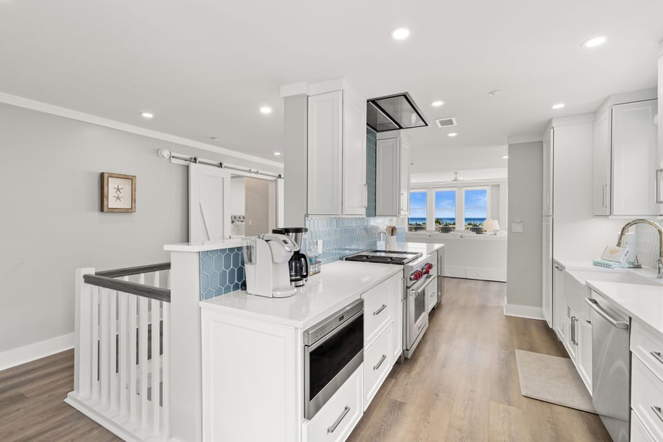 Your gourmet kitchen features gleaming white cabinets, premium appliances, and stunning blue ocean views that make cooking feel like a vacation.