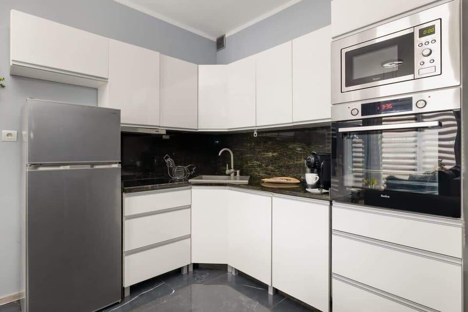 A sleek white kitchen with black countertops and integrated appliances.
