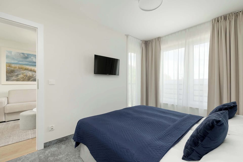 Stylish bedroom with soft textiles and a mounted TV for evening entertainment. The decor is simple and restful.